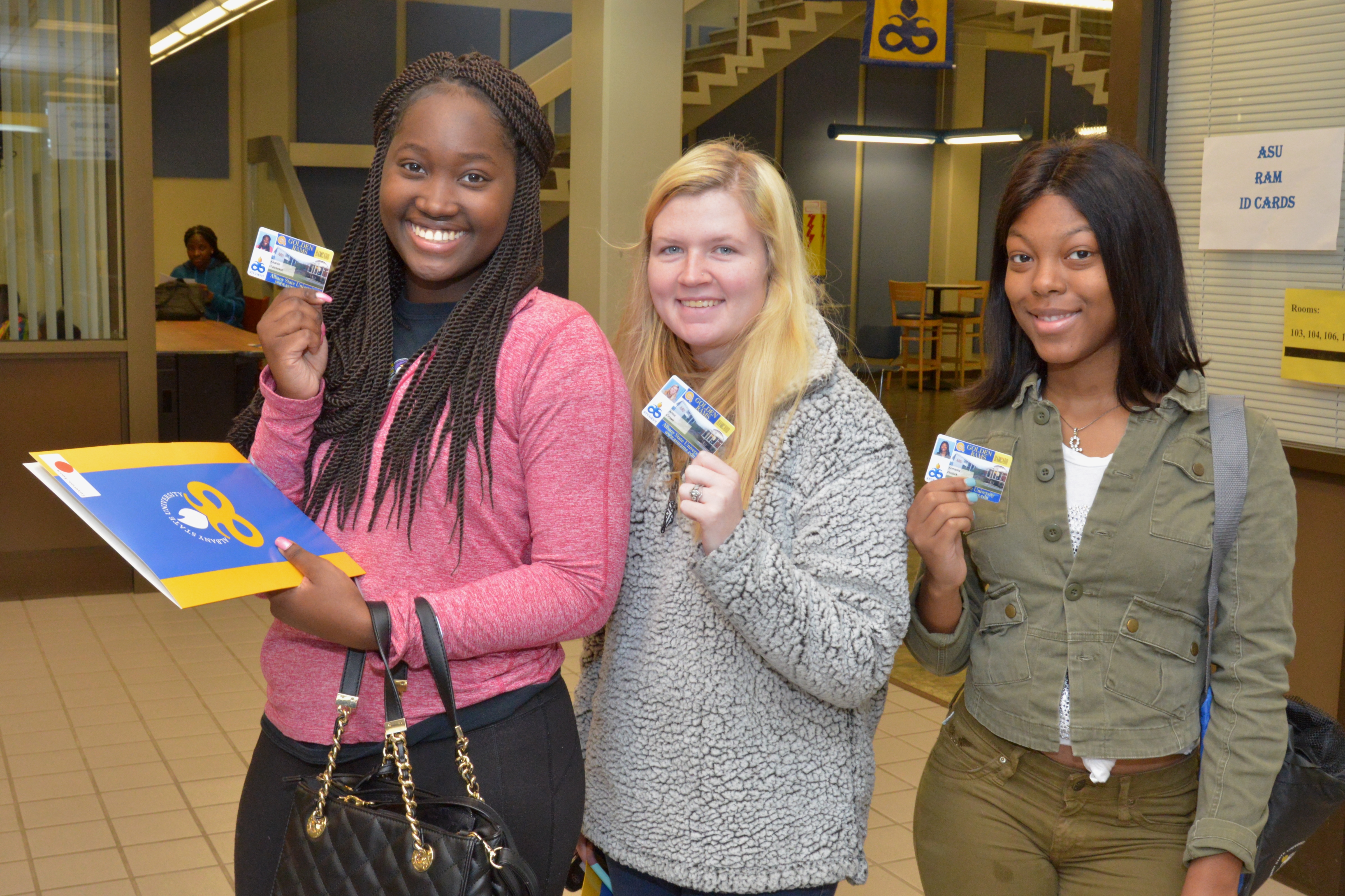 students smiling holding ID cards